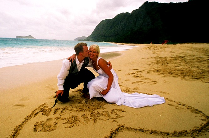 writing their names on the sand at thier beach wedding in Hawaii