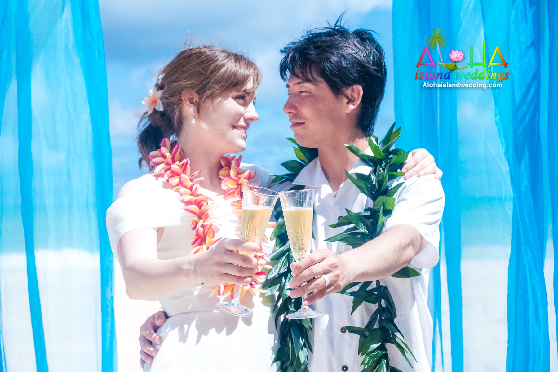 The couple do their firt wedding tooast with guava juice under their beach arch in Waimanalo