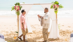 arch in Hawaii with groom giving flower lei