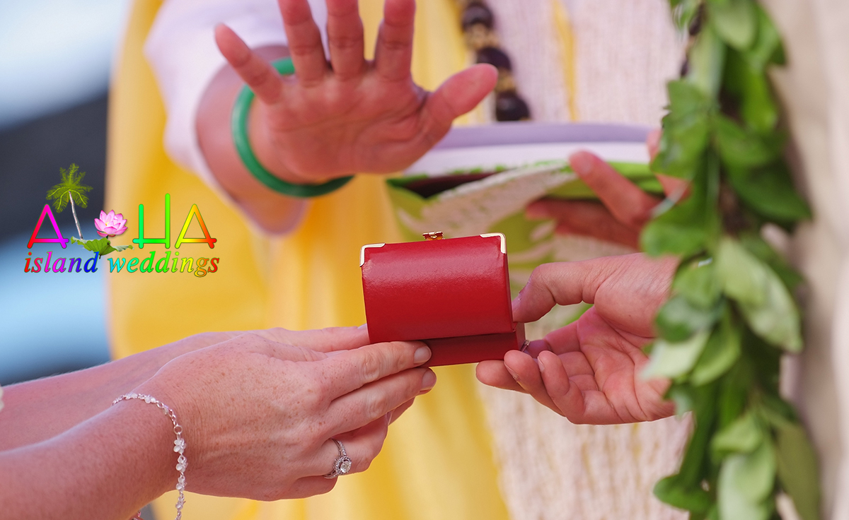 Wedding rings in a red box being blessed in a ti leaf during a Hawaiian ceremony
