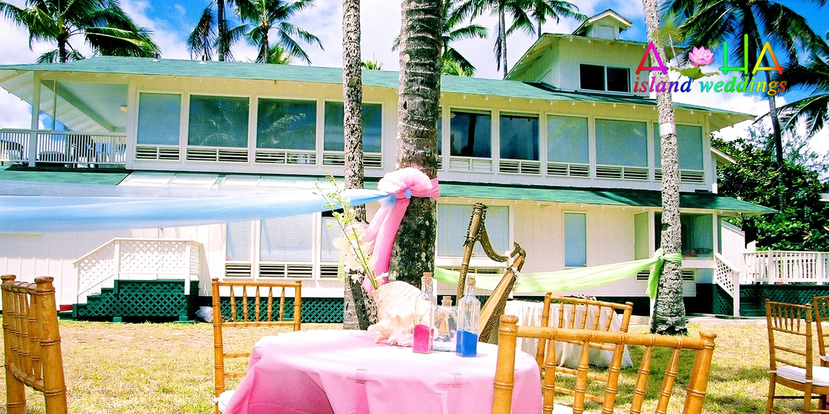 Reception tables with pink tablecloths on the lawn in front of the estate house
