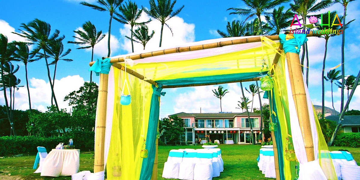 Yellow and white draped wedding canopy on the lawn in front of the estate house