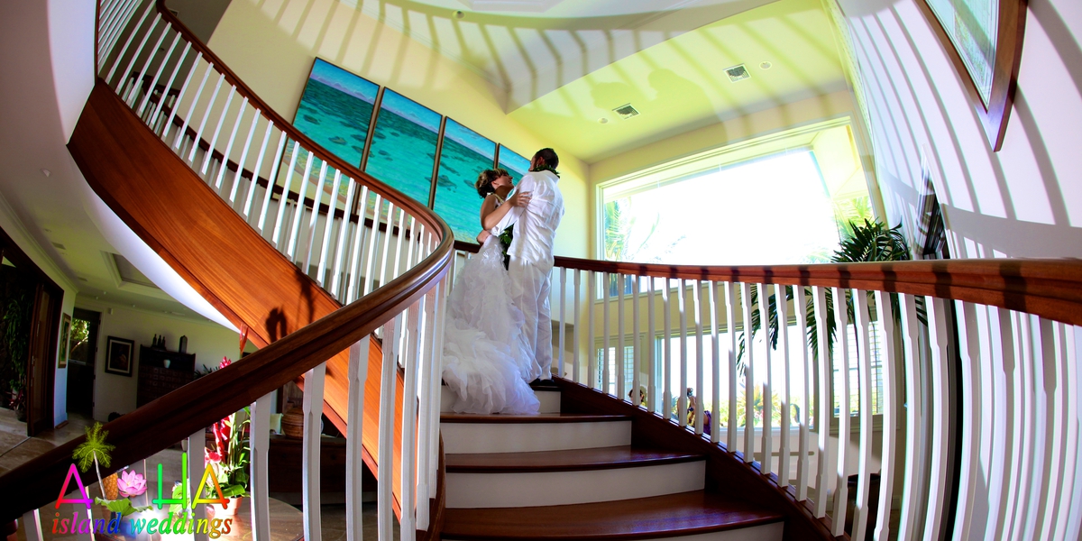 Couple standing on the curved wooden staircase inside the estate house