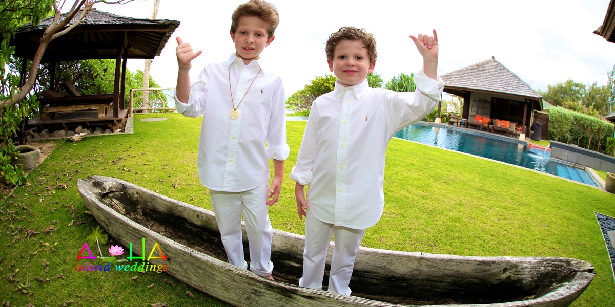 Two young boys in white outfits standing in a canoe on the estate lawn