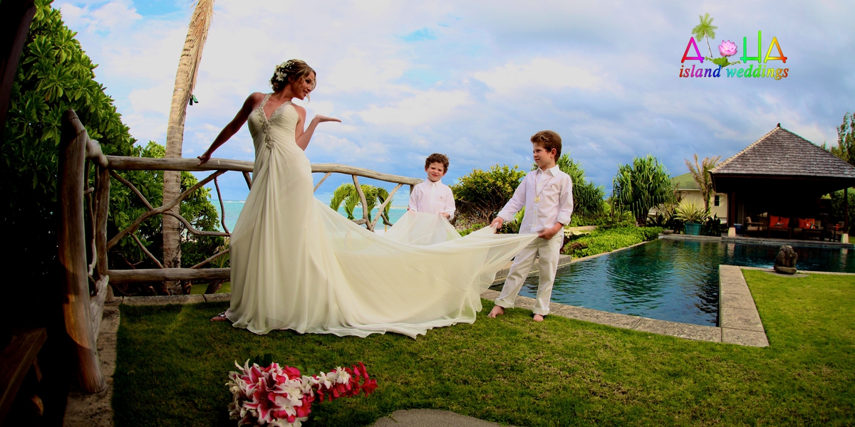 Bride in a flowing gown and groom on the garden terrace beside the estate house pool