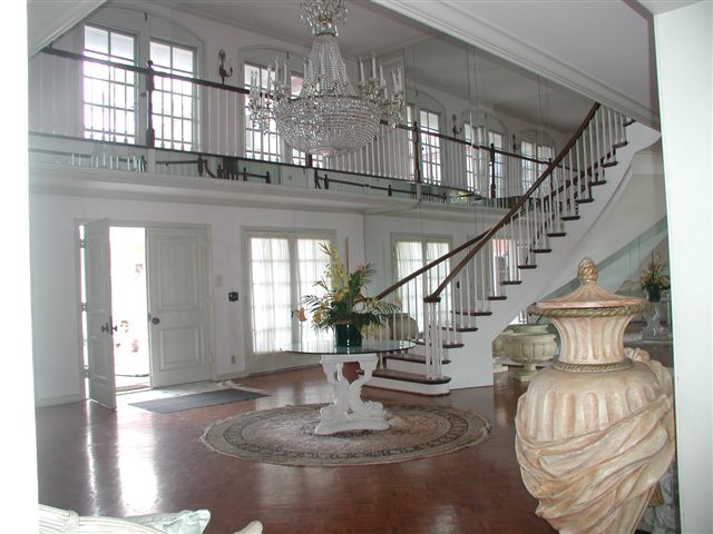 Entrance hall of the pink house with a grand staircase and chandelier
