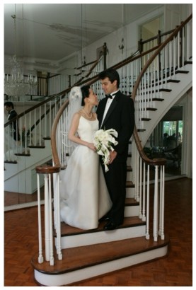 Bride and groom posing on a white spiral staircase inside the estate house