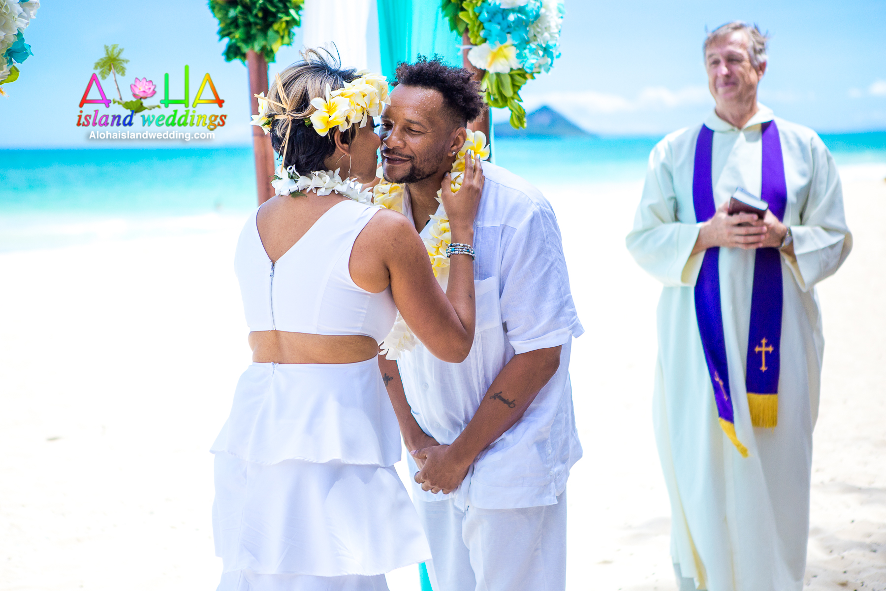 Adrienne and Cedric sharing a smile after their lei exchange as the minister looks on