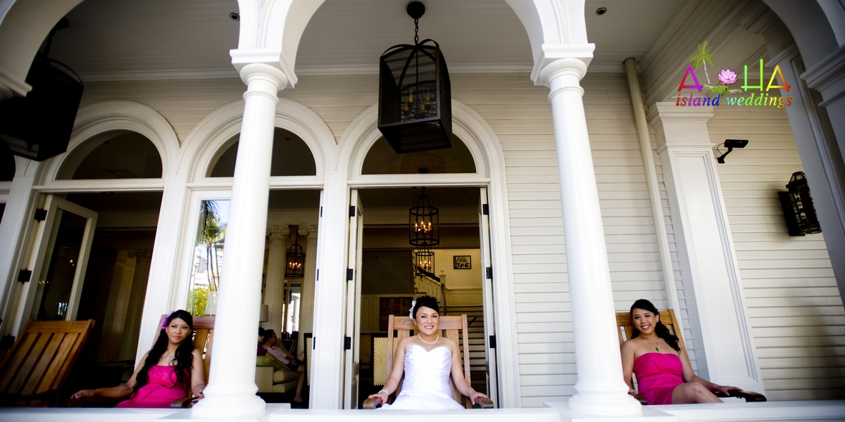 Bride and bridesmaids sitting on the white veranda of the Royal Hawaiian Hotel