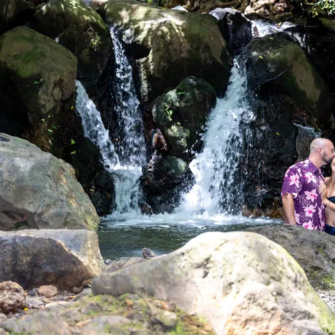 Couple standing by a rainforest waterfall on Oahu
