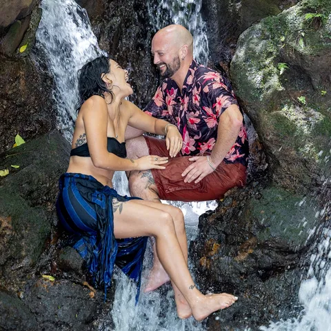 Engaged couple laughing together on the rocks of a waterfall