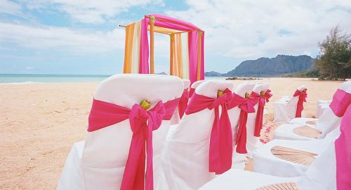 Orange white and dark pink make for the theme of this beach wedding