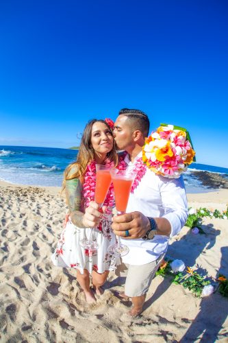 Bride smile as she gets a kiss from the groom before the wedding start on the beach at Makapuu