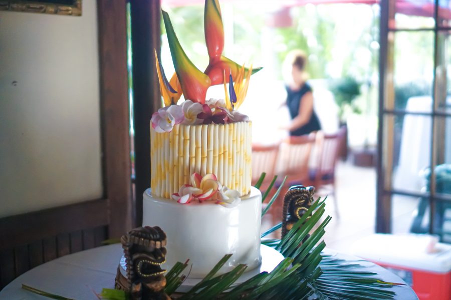 Pink and rainbow plumeria's with birds of paradise decorate the Hawaiian wedding cake .