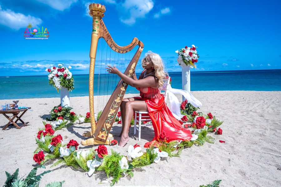 playing harp at ceremony on beach in her red dress at her Vow renewal in Hawaii