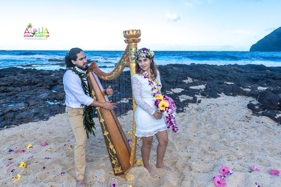 Groom pretends to play the harp for his bride with a colorful tropical bouquet