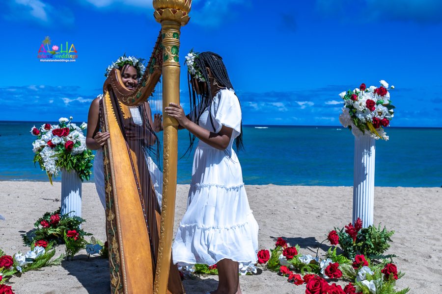 flower girls strumming the harp strings after their parents 10 year vow renewal in Hawaii
